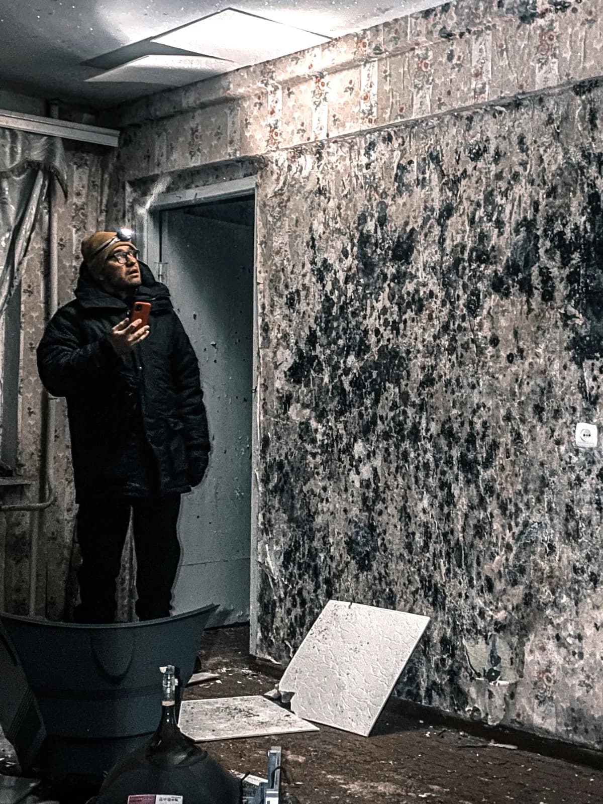 A worker checking a room with widespread mold growth on the walls